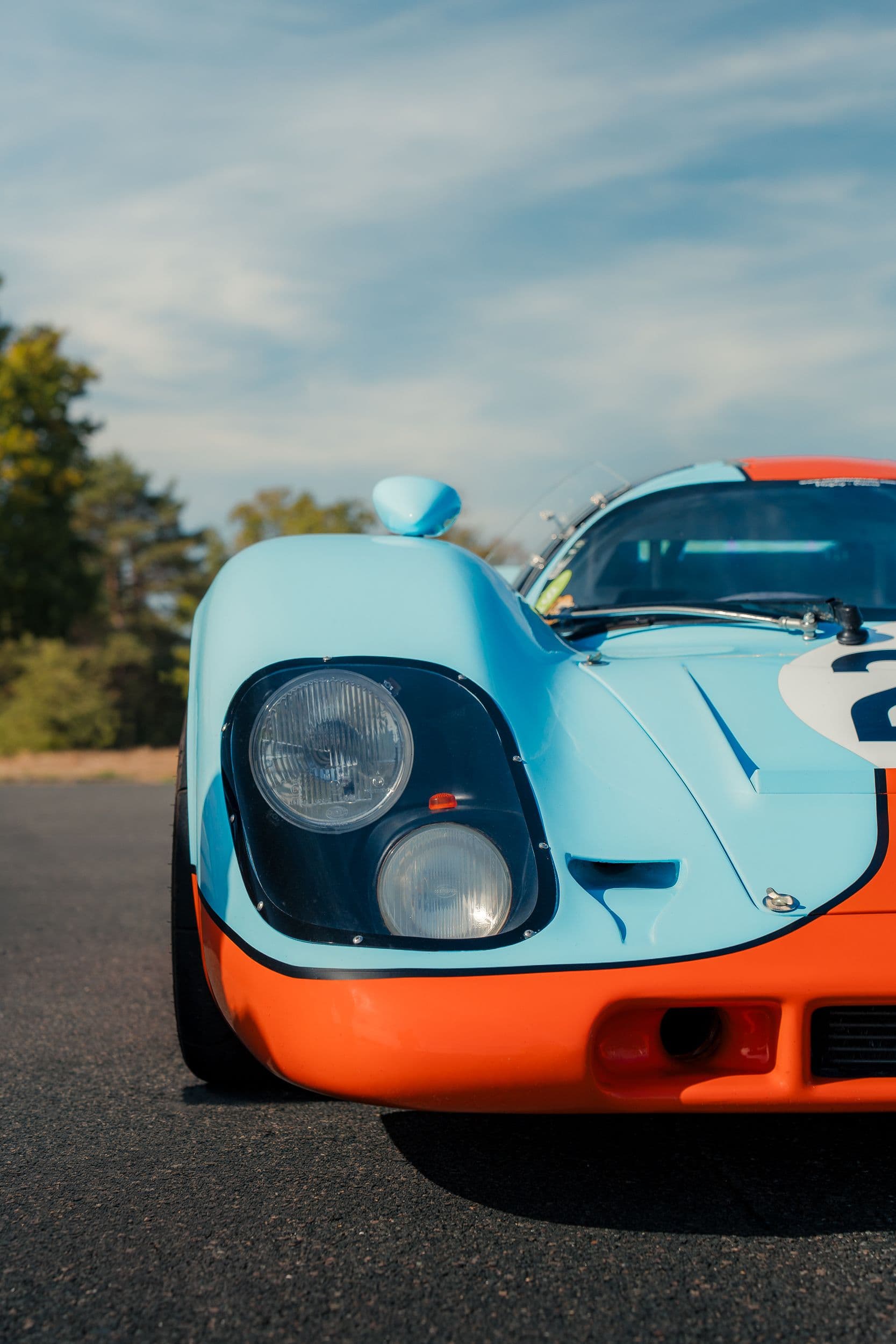 Deux phares superposés sous une protection transparente sur l’avant bleu d’une Porsche 917 Replica.