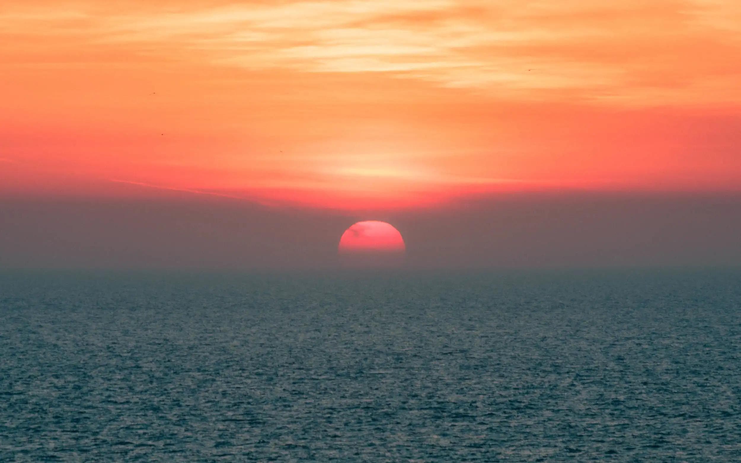 Coucher de soleil noyé dans une brume rosée au-dessus de la mer à Deauville, image poétique de la série La Pupille d’Hélios par Arthur Monteil.