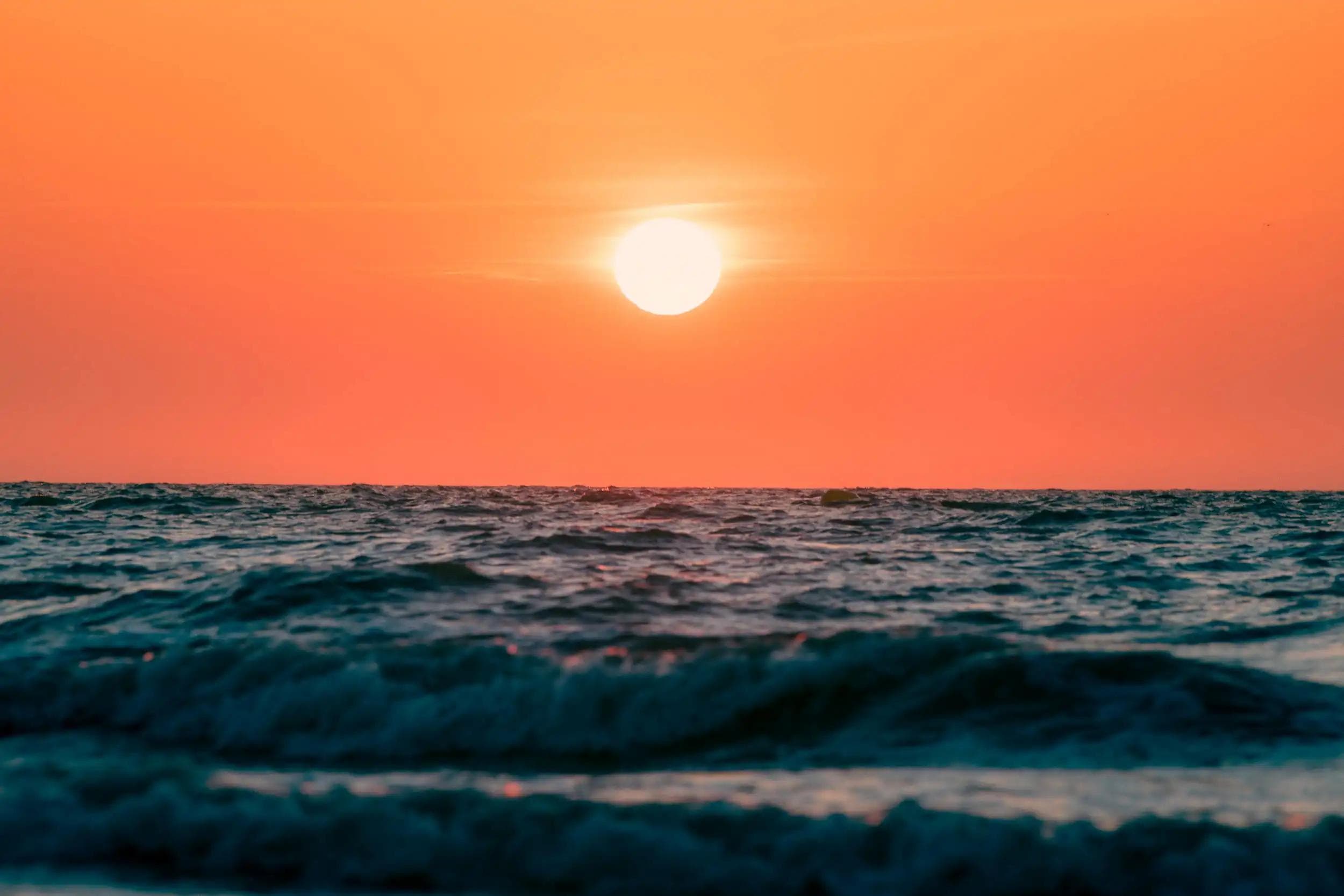 Photographie du soleil brillant au-dessus des vagues à Deauville dans un ciel orange intense, issue de la série La Pupille d’Hélios d’Arthur Monteil.
