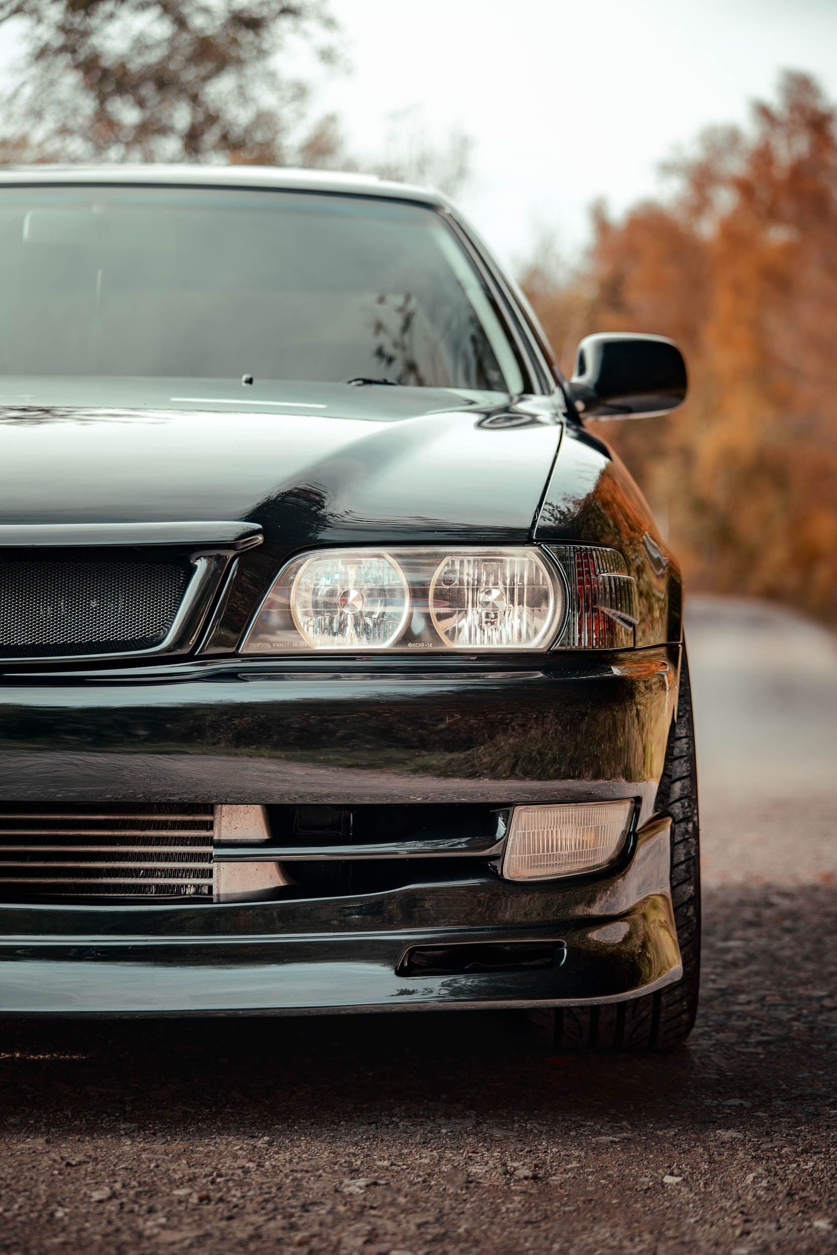 Gros plan face avant Toyota Chaser JZX100, phares doubles et calandre, berline sportive japonaise ambiance automne