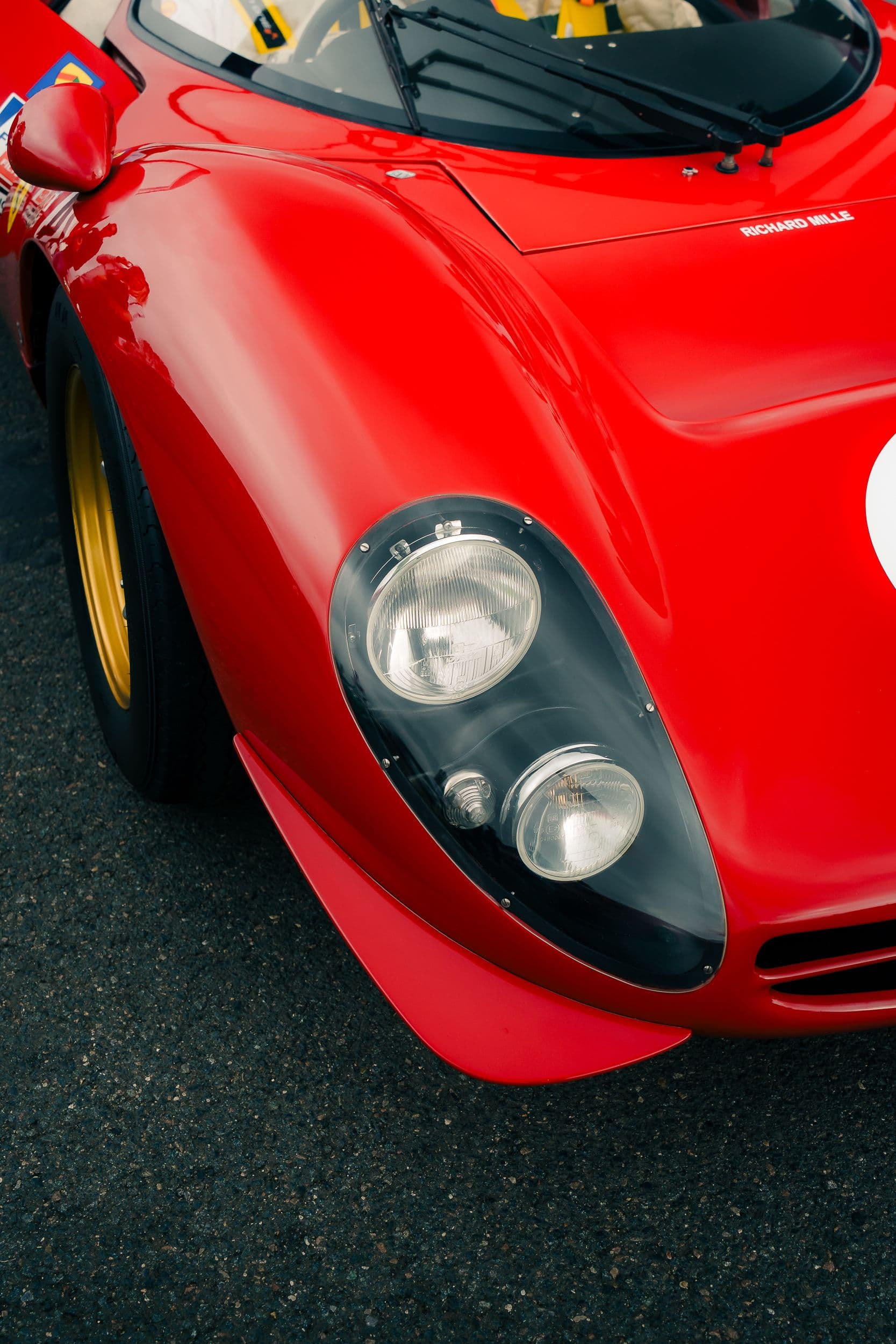 Gros plan en plongée sur les phares et l’aile rouge d’une Ferrari 330 P4 Replica.
