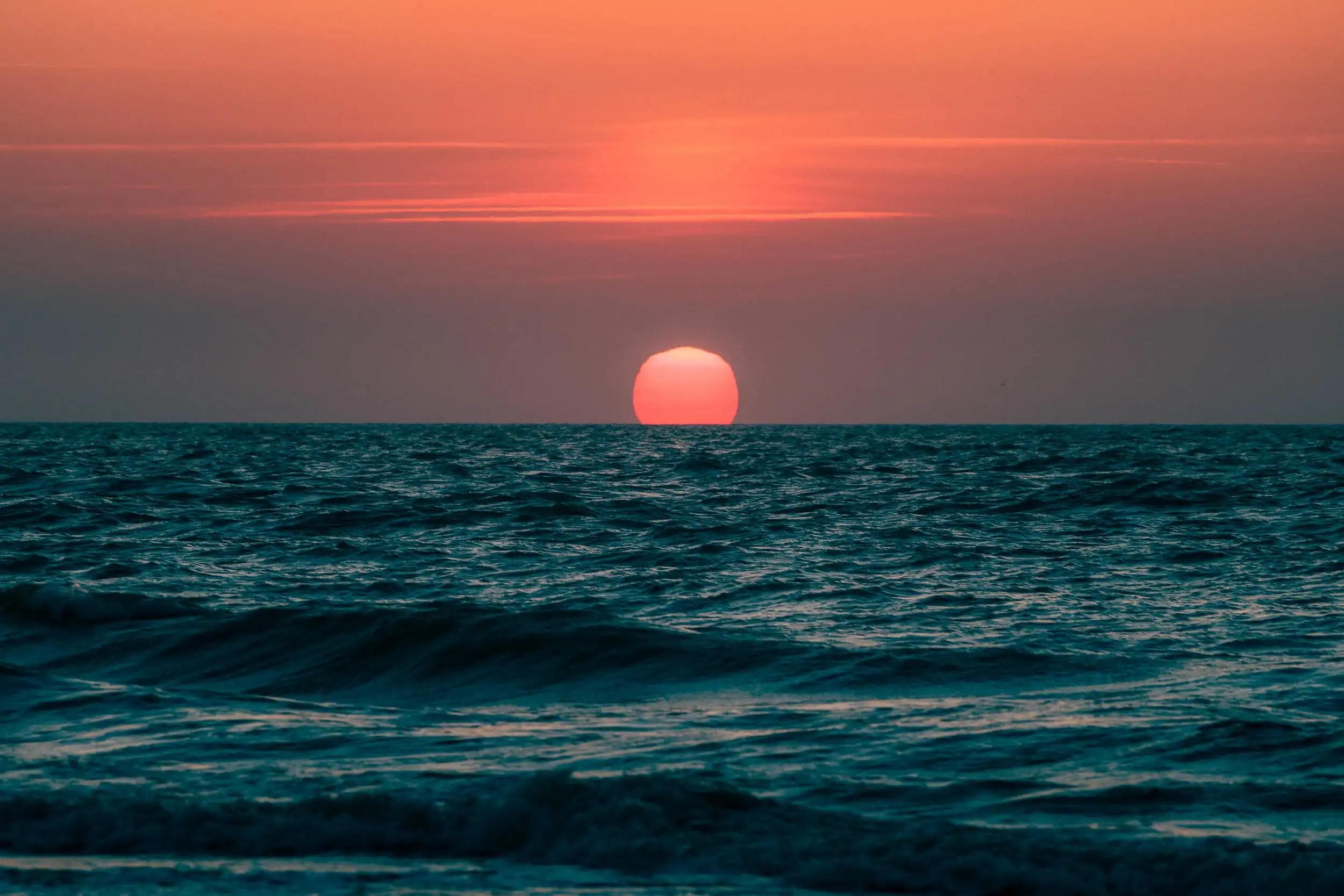 Coucher de soleil à Deauville avec l’astre rougeoyant descendant dans l’horizon marin, photographie artistique de la série La Pupille d’Hélios réalisée par Arthur Monteil.