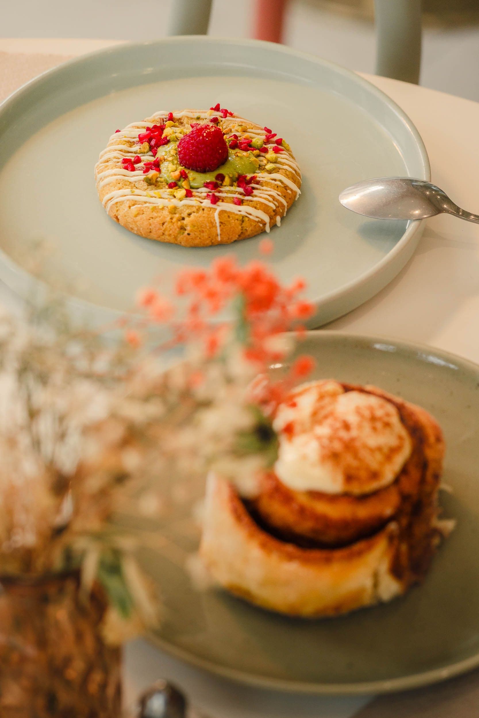 Cookie pistache-framboise et cinnamon roll avec fleurs séchées, photographie culinaire pour identité visuelle de coffee shop