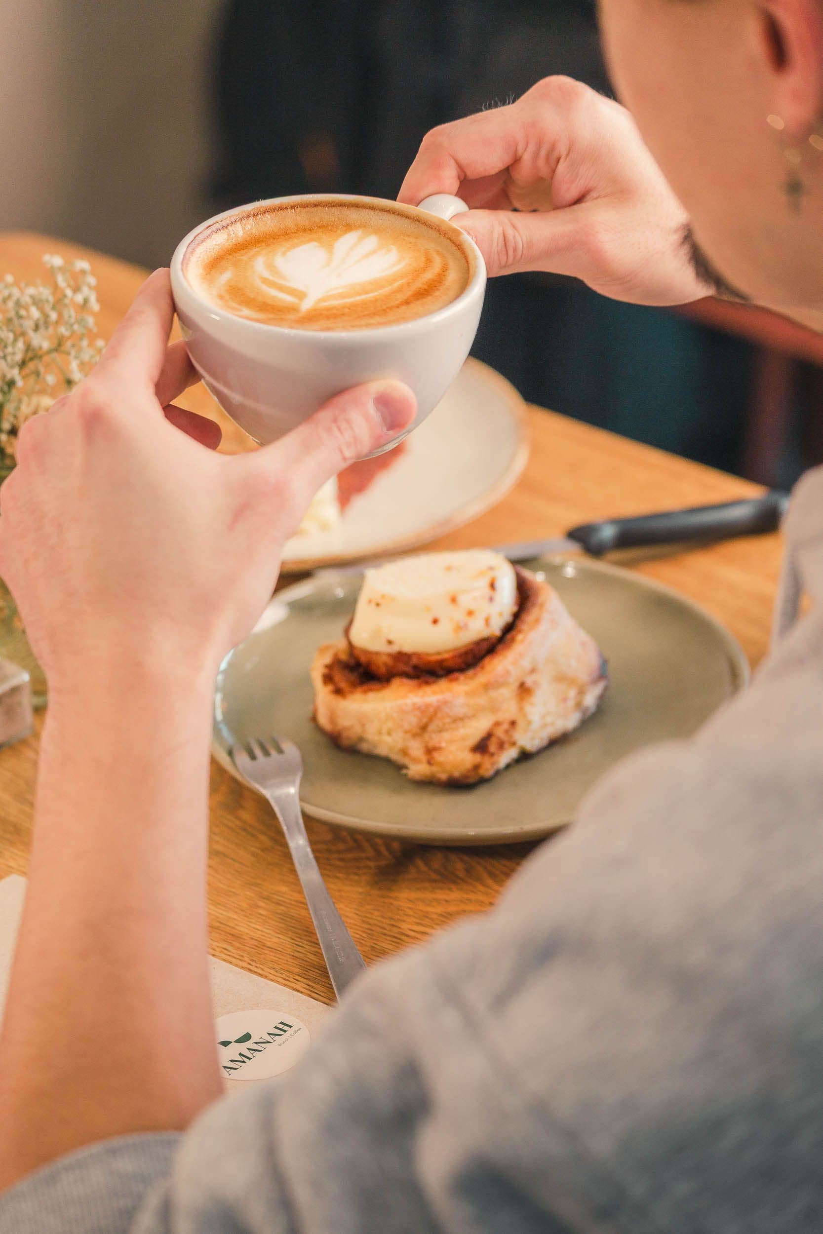 Cappuccino avec latte art et cinnamon roll sur table en bois, photographie de produits pour coffee shop artisanal