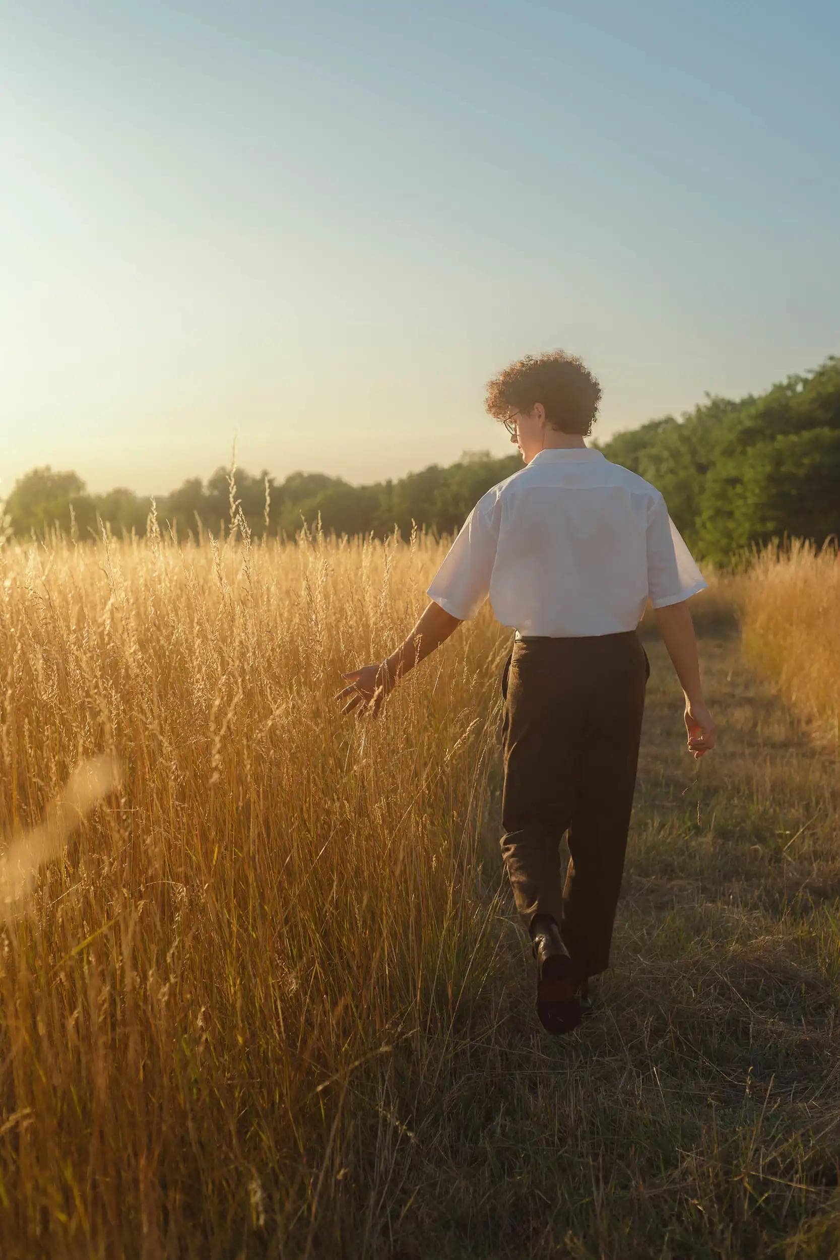 Jeune homme marchant dans un champ au coucher du soleil à Bussy-Saint-Georges, photographie narrative de liberté.