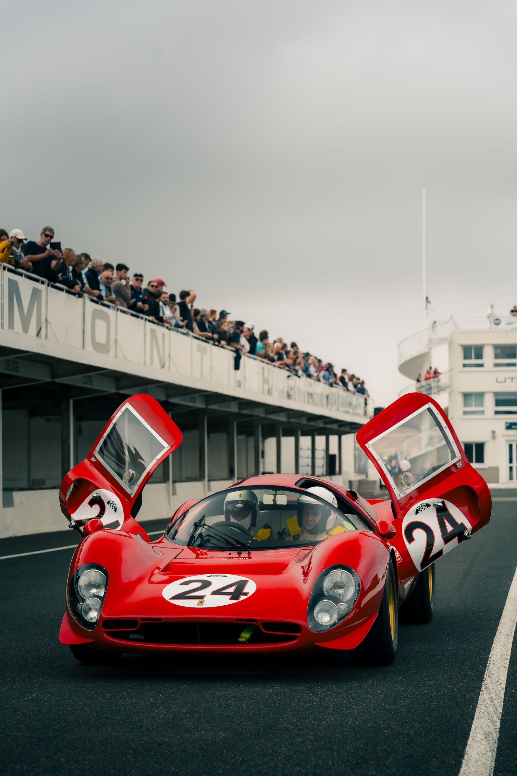 Ferrari 330 P4 Replica rouge numéro 24 vue de face, portes relevées et deux occupants casqués.