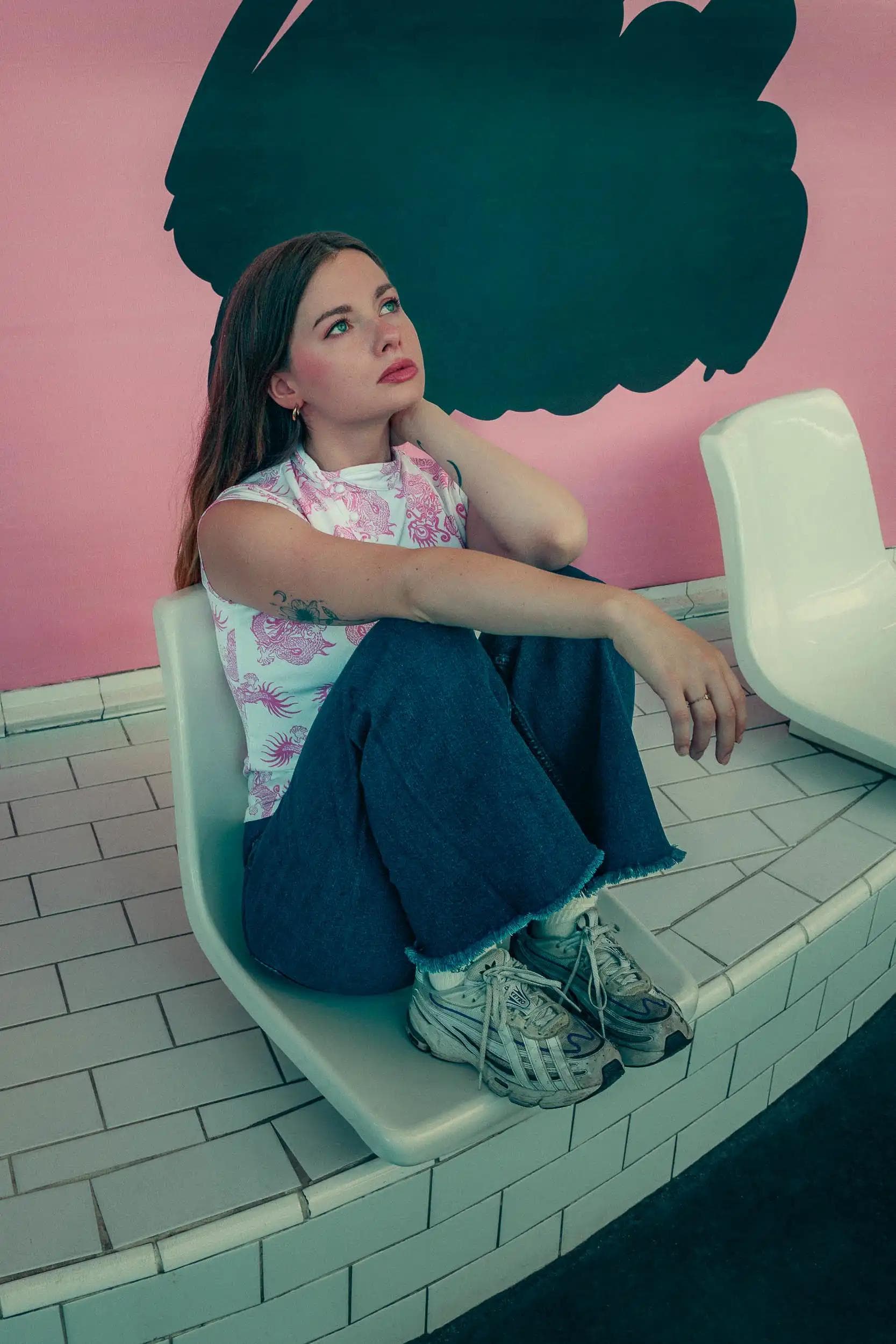 Portrait cinématographique d’une femme assise dans une ambiance colorée, regard perdu, photographie symbolisant l’introspection et réalisée à Paris par Arthur Monteil.