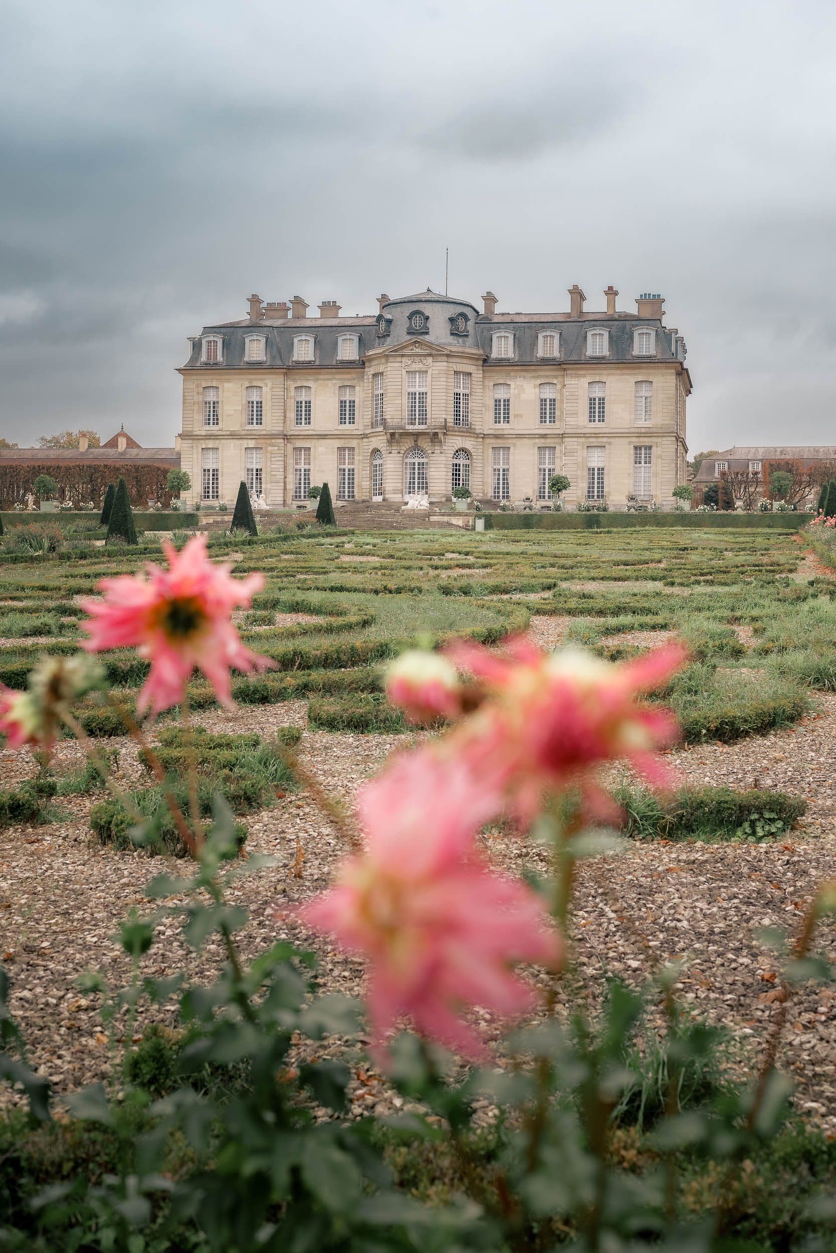 Façade du Château de Champs-sur-Marne vue depuis les jardins à la française avec roses au premier plan