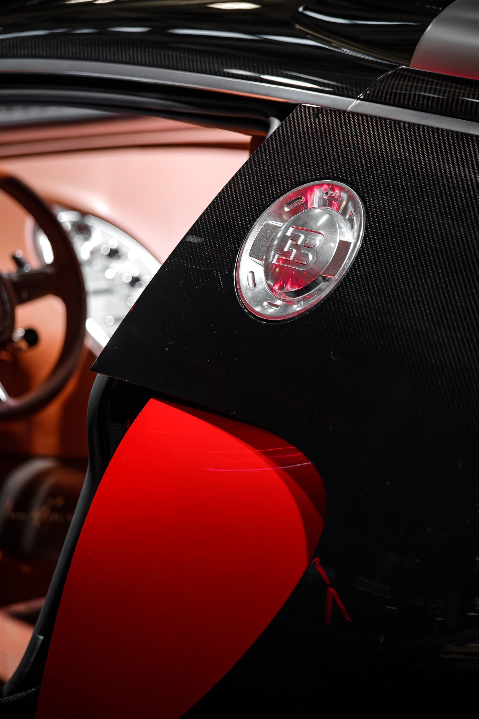 Gros plan sur un détail de carrosserie en carbone avec le logo EB sur la Bugatti F.K.P Hommage, au Rétromobile 2026.