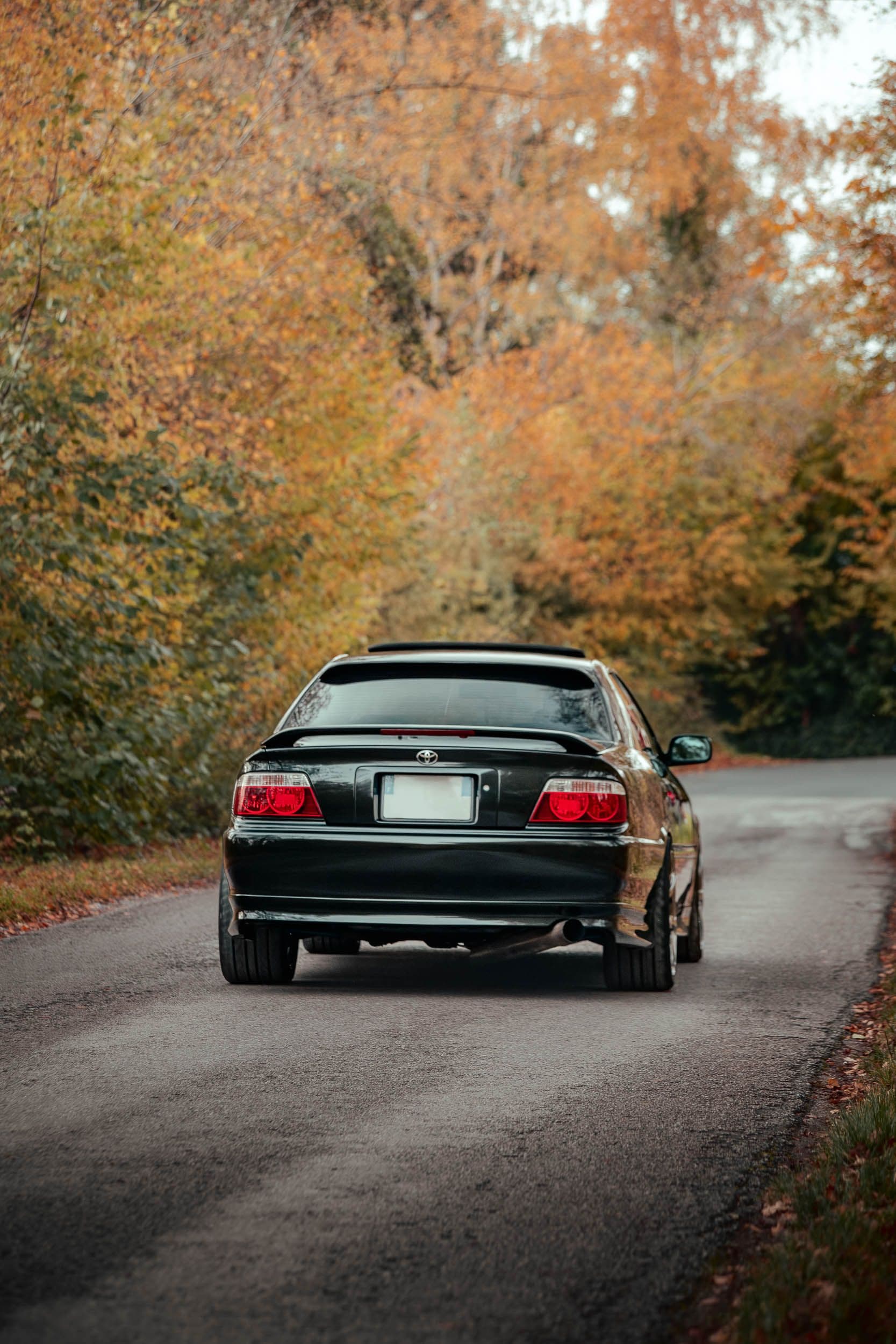 Toyota Chaser JZX100 vue arrière sur route automne, feux rouges signature, berline sportive japonaise photographie Arthur Monteil