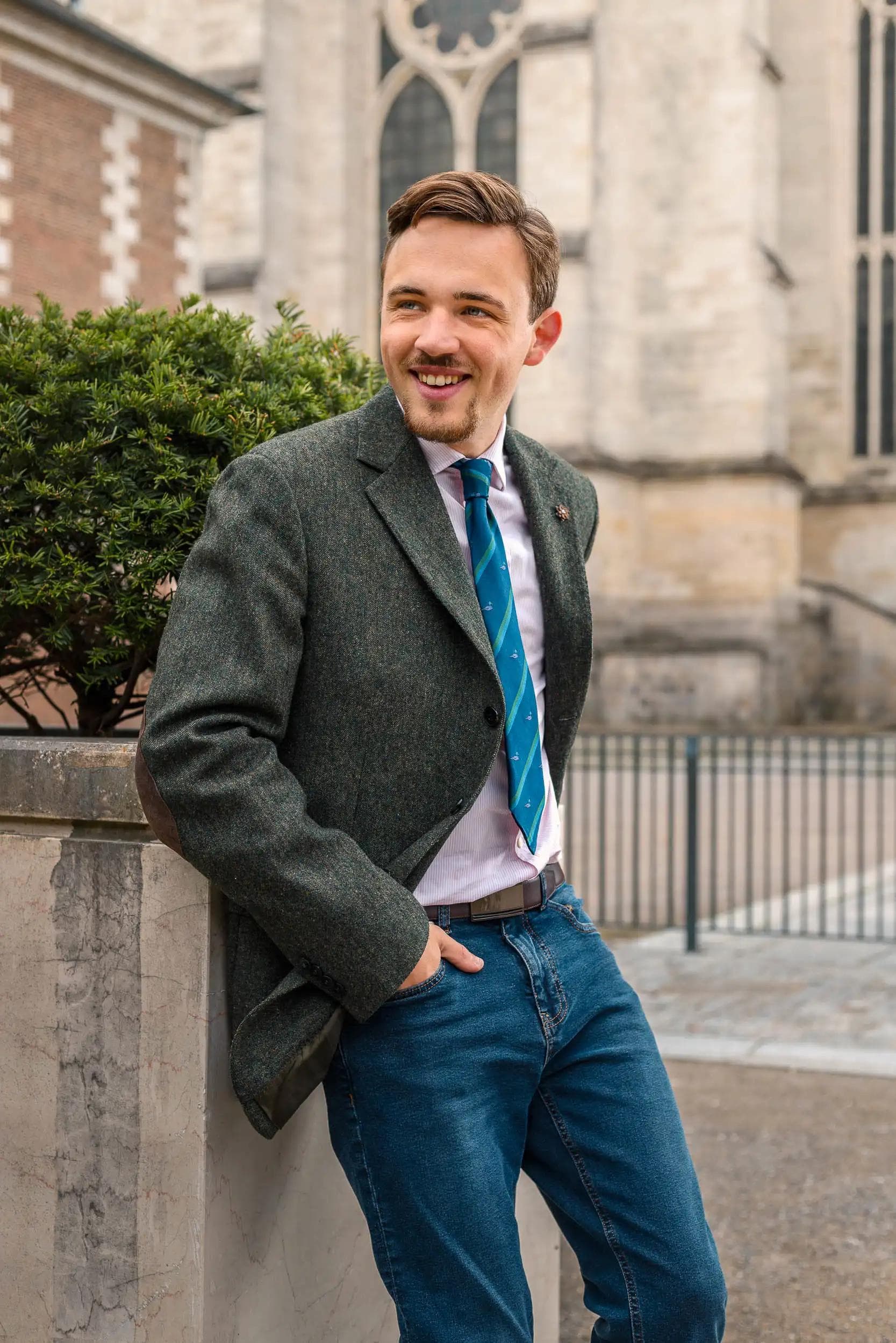 Portrait lifestyle d’un homme souriant devant une architecture d’Amiens, photographié dans un style éditorial élégant par Arthur Monteil.