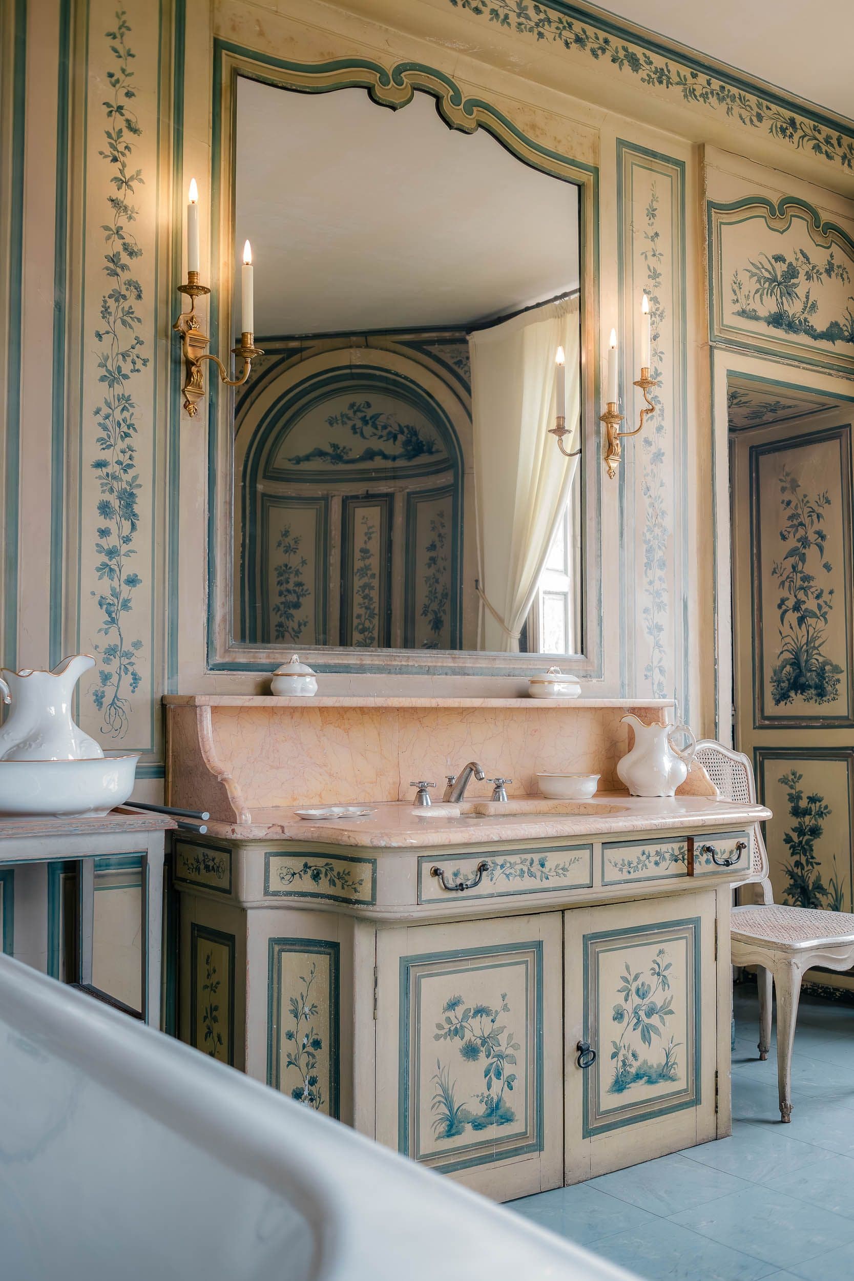 Salle de bain historique avec vasque en marbre, boiseries peintes bleues et miroir doré, XVIIIe siècle