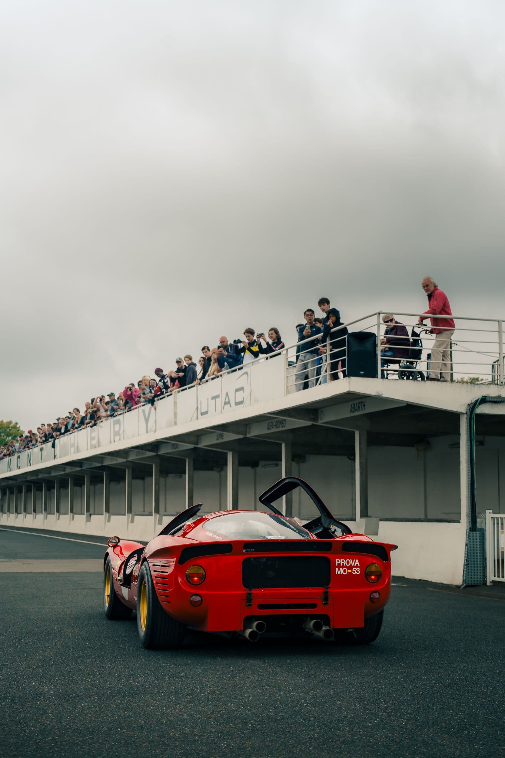 Ferrari 330 P4 Replica rouge vue de l’arrière, portes relevées, sous les spectateurs de Montlhéry.
