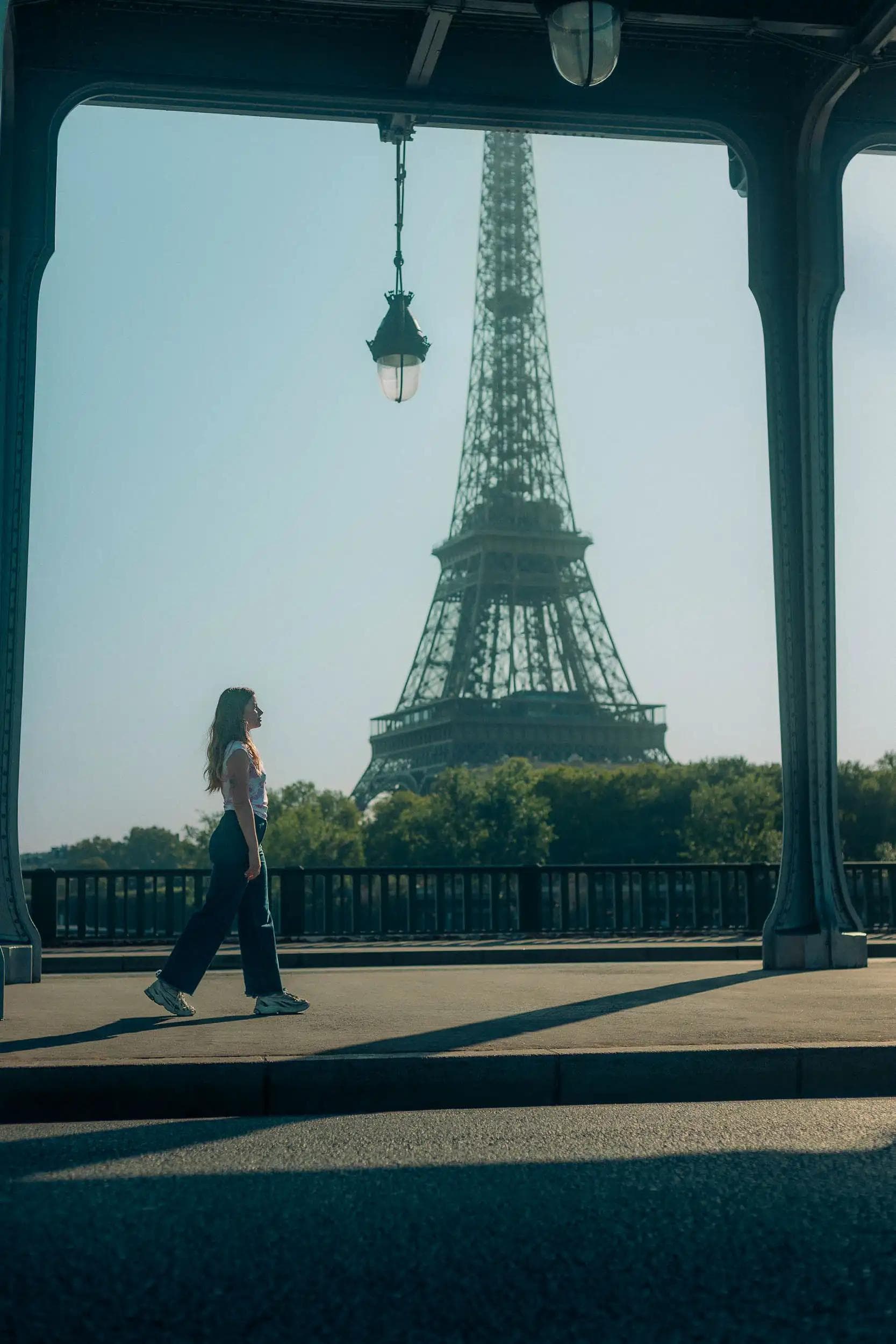 Portrait cinématographique d’une femme marchant sous le pont de Bir-Hakeim avec la tour Eiffel en arrière-plan, réalisé par Arthur Monteil pour un projet visuel inspiré d’Inception.