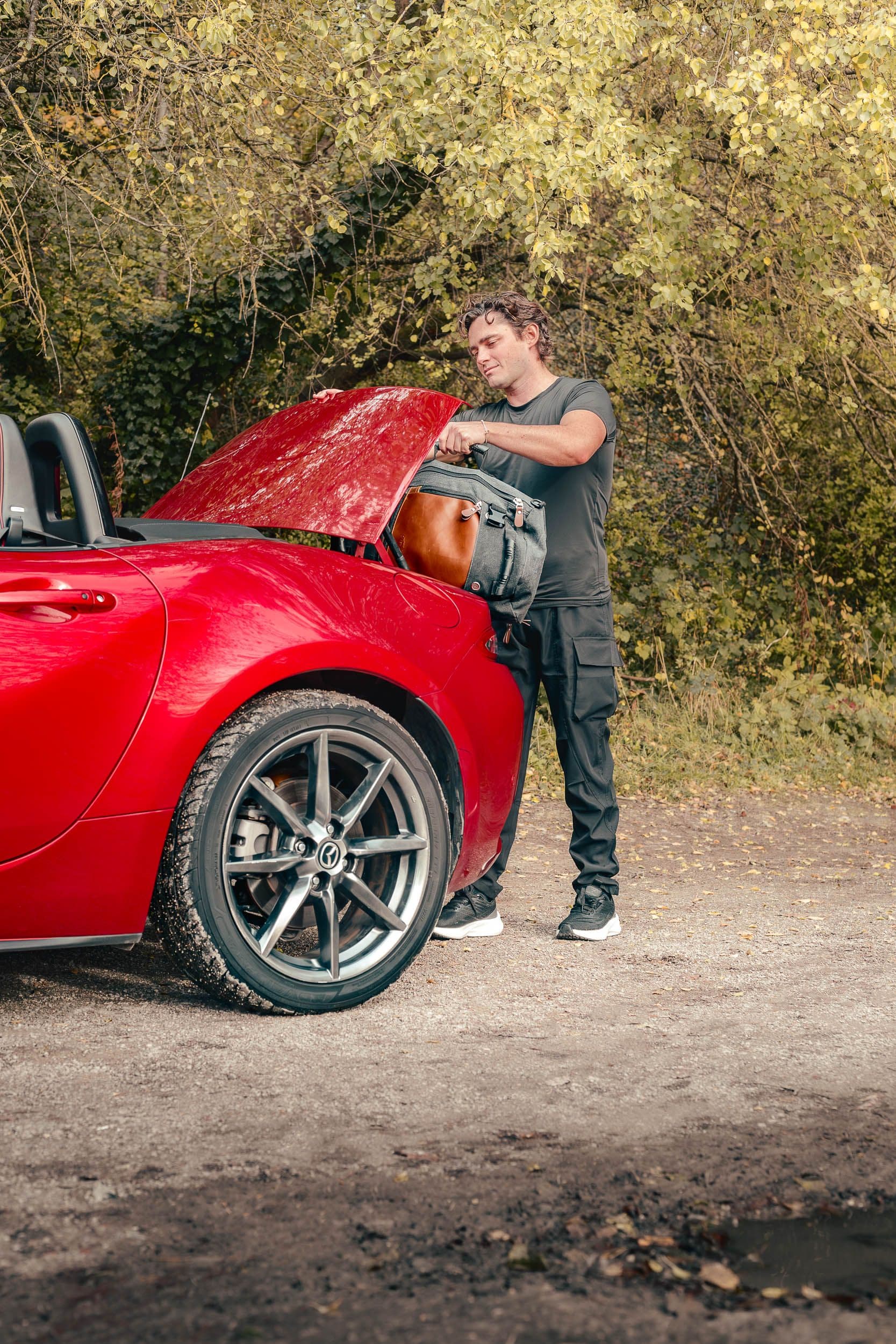 Conducteur préparant sa Mazda MX-5 roadster rouge capot ouvert, scène lifestyle automobile par Arthur Monteil
