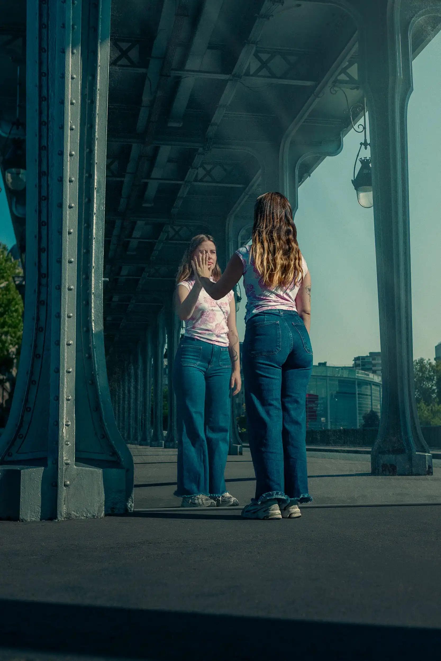 Portrait symbolique d’une femme se tenant face à son reflet dans un panneau miroir sous le pont de Bir-Hakeim, Paris, photographie inspirée de la scène des miroirs dans Inception et axée sur la notion d’introspection.
