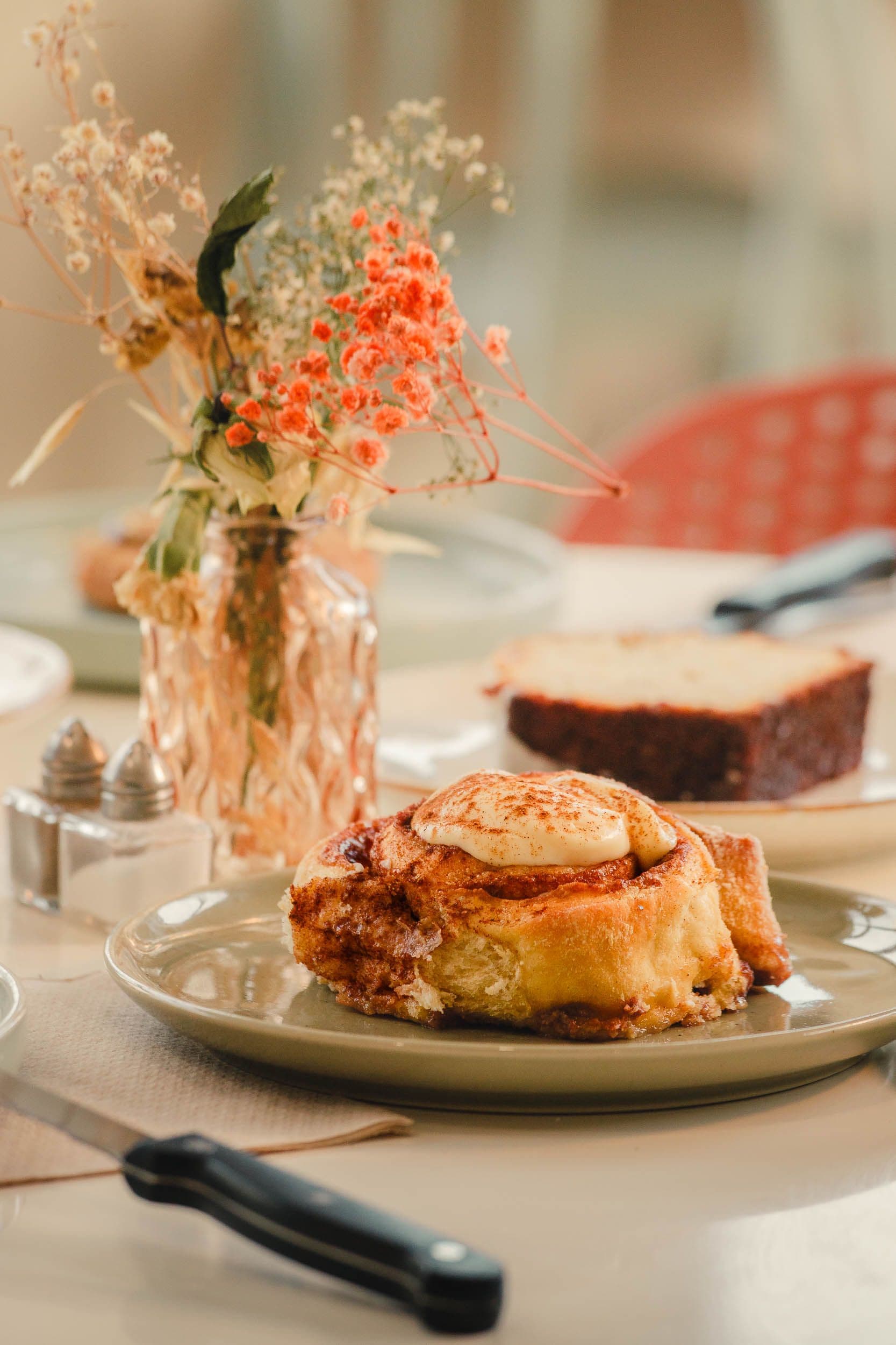 Cinnamon roll artisanal avec glaçage et fleurs séchées, photographie culinaire pour Amanah Coffee Shop à Bussy-Saint-Georges par Arthur Monteil