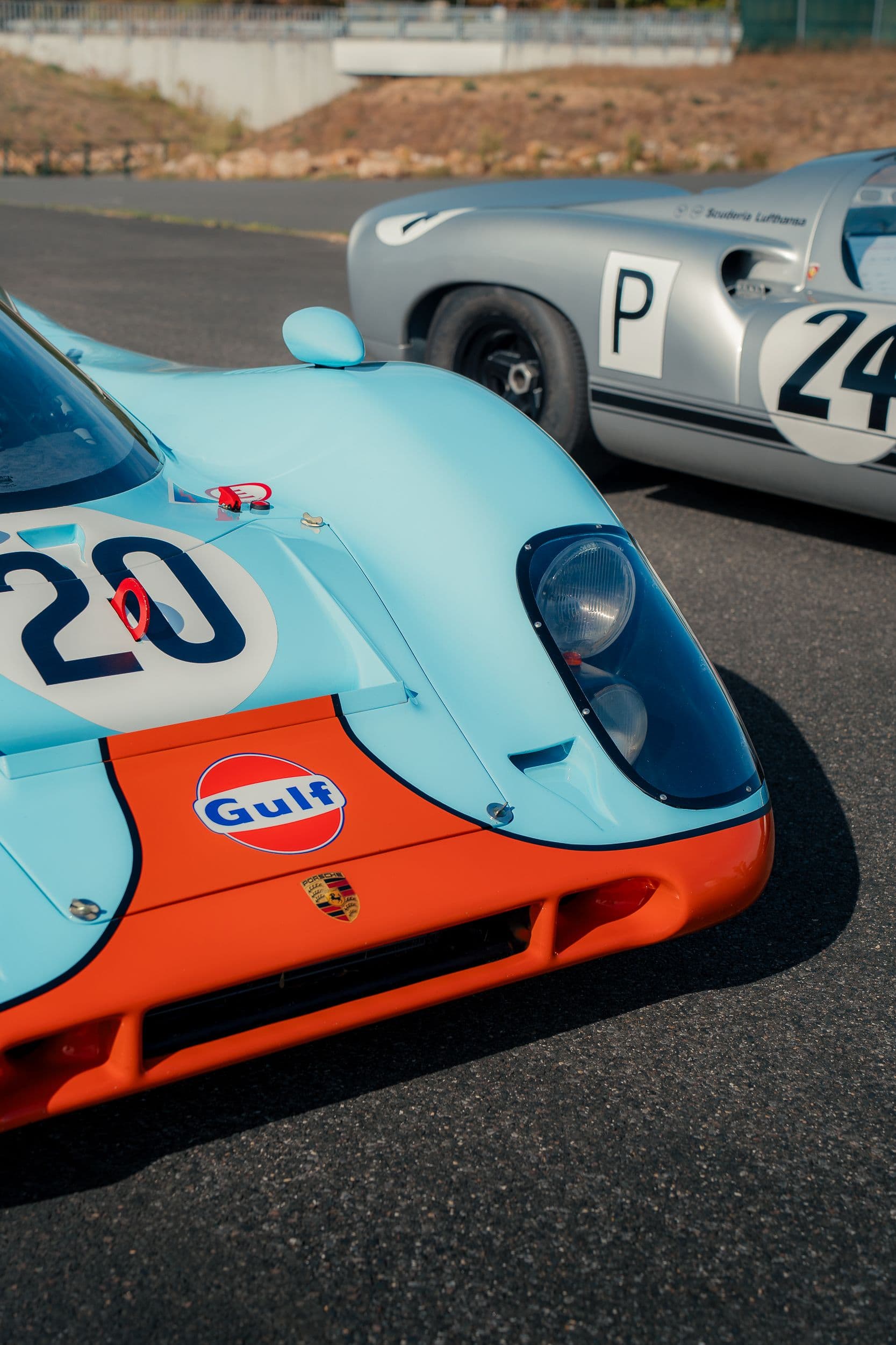 Avant bleu et orange d’une Porsche 917 Replica, avec une Porsche 910 argentée derrière.