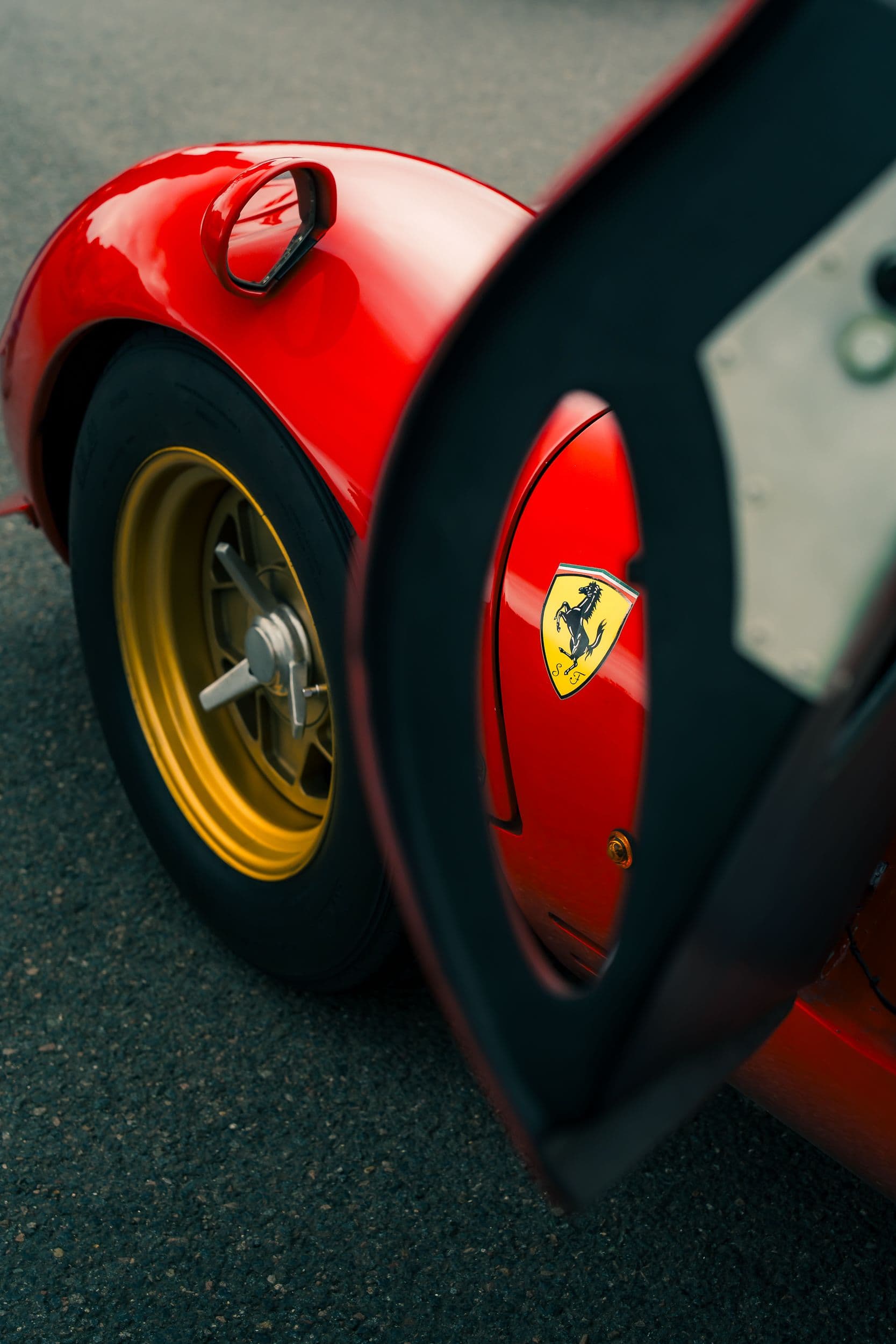 Écusson Ferrari et roue dorée d’une 330 P4 Replica, vus à travers la porte ouverte.
