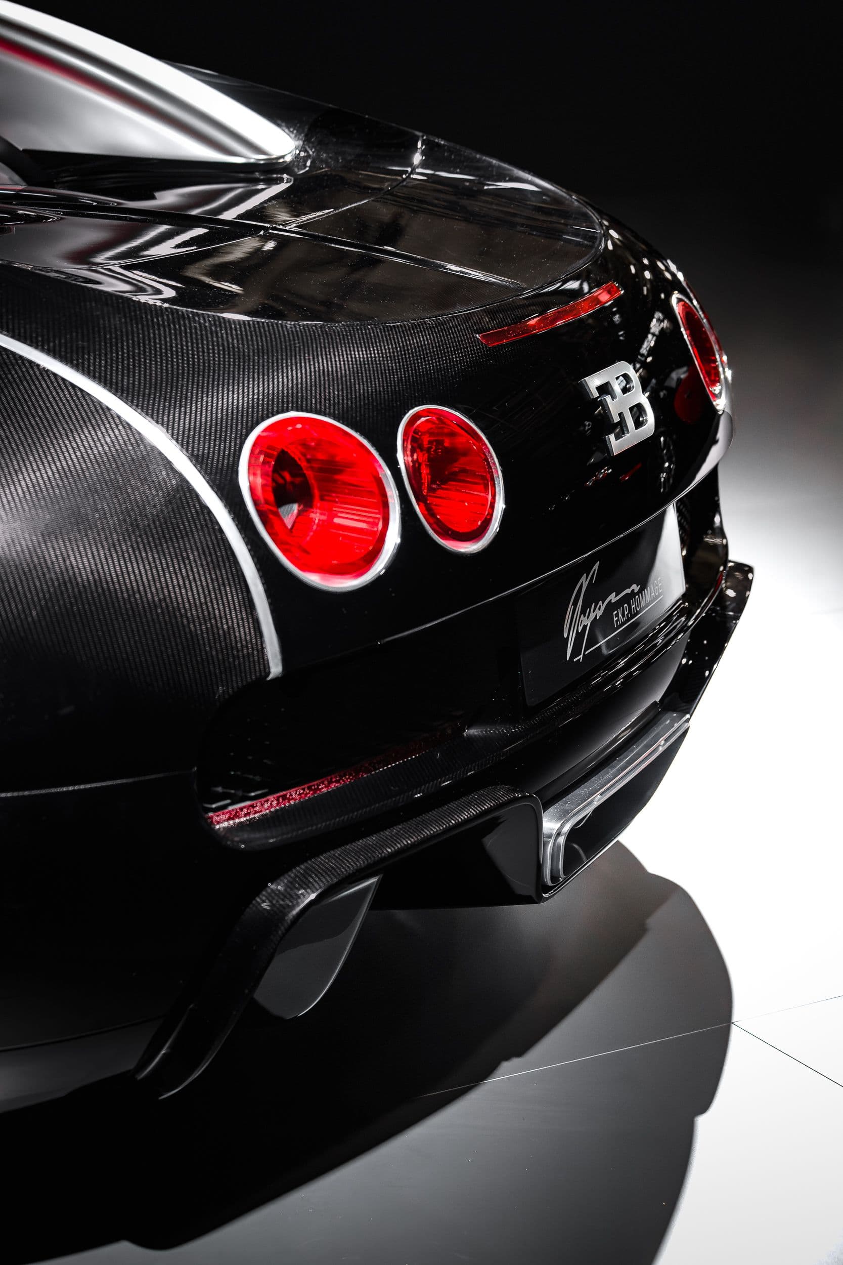 Détail arrière de la Bugatti F.K.P Hommage avec feux ronds rouges et logo Bugatti, sur carrosserie carbone, au Rétromobile 2026.