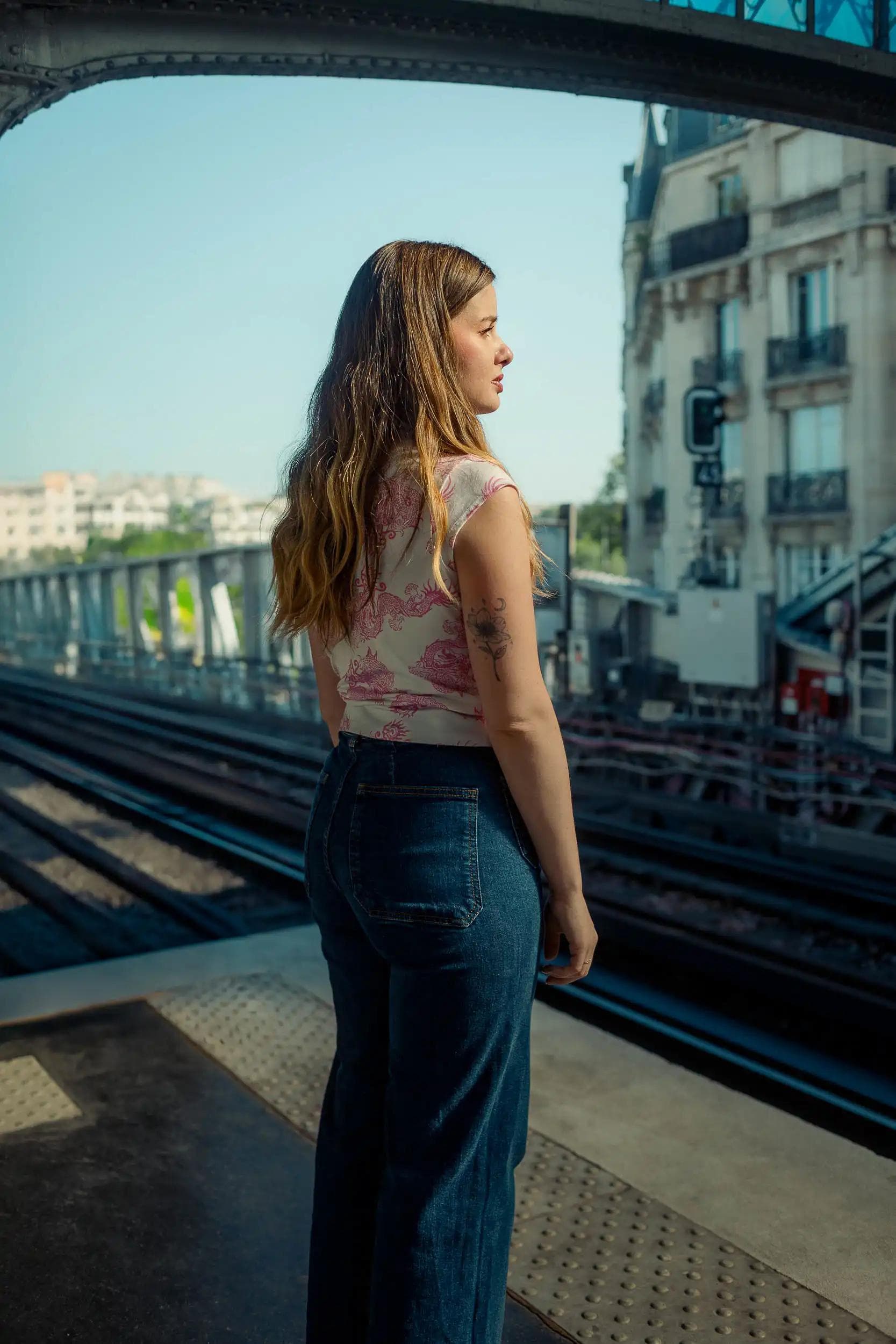 Portrait cinématographique d’une femme regardant les rails du métro à Paris, photographiée au pont de Bir-Hakeim par Arthur Monteil dans une ambiance inspirée d’Inception et axée sur l’introspection.