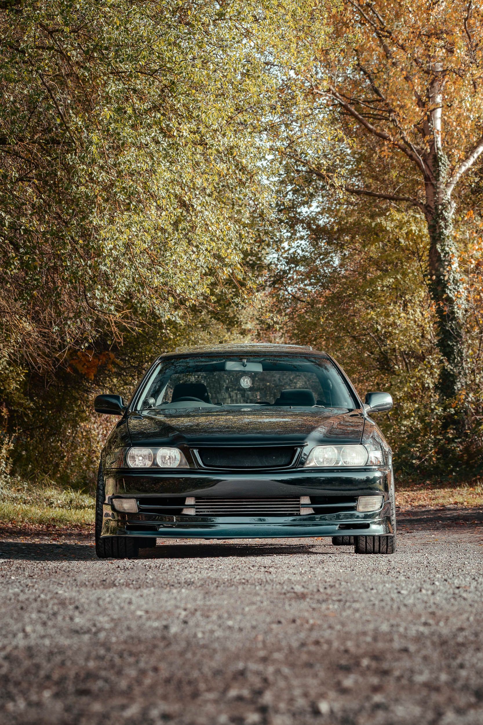 Toyota Chaser JZX100 face avant complète sur route automne, berline sportive JDM stance bas, photographie automobile Arthur Monteil