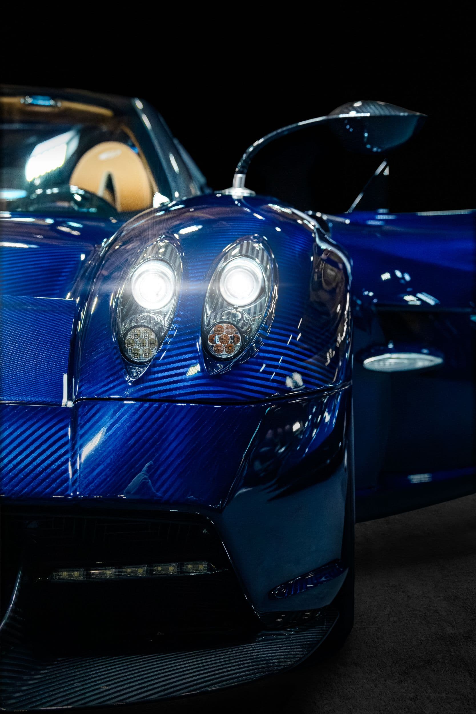 Gros plan sur la face avant de la Pagani Huayra, signature lumineuse et détails de carrosserie.