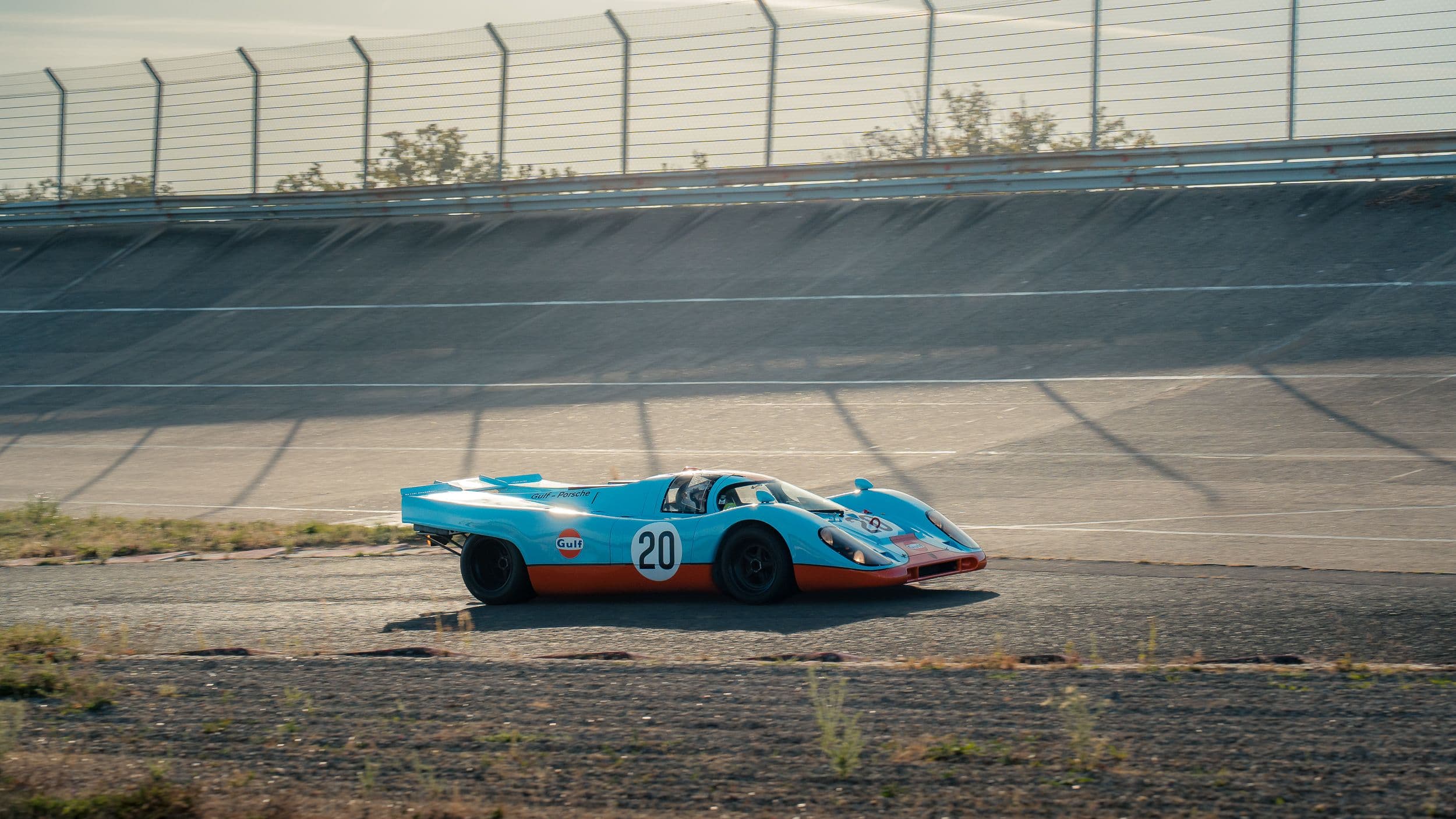Porsche 917 Replica bleue et orange roulant au pied du virage relevé de Montlhéry.