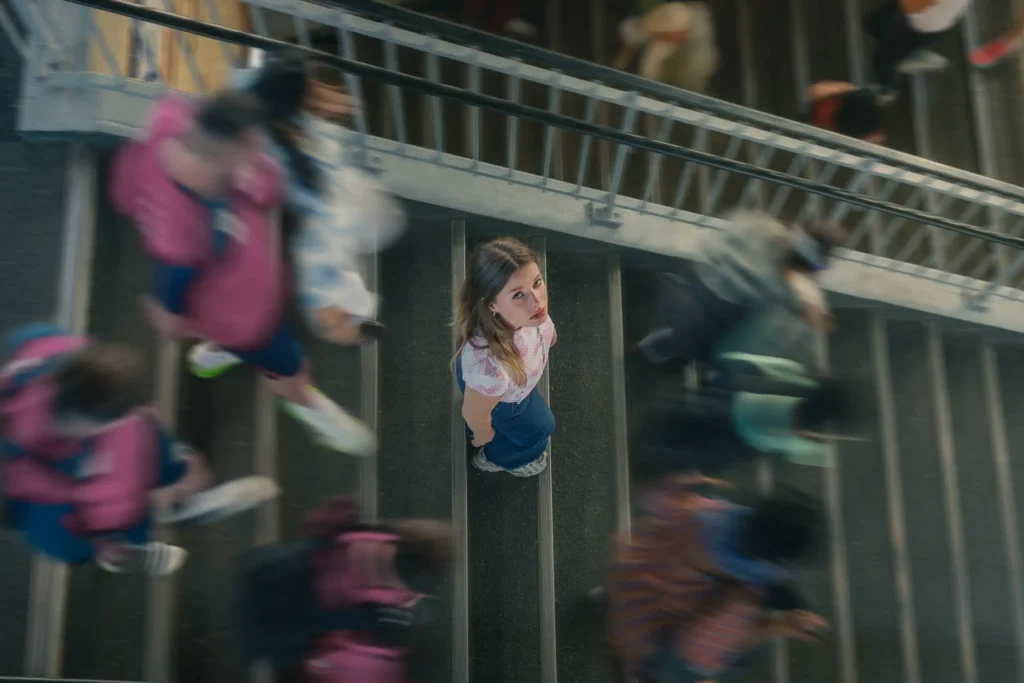 Portrait créatif d’une femme immobile sur un escalier à Paris avec foule floue autour.