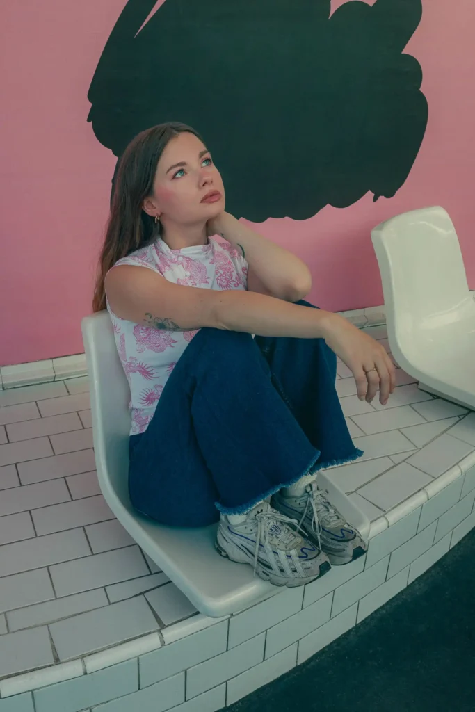 Portrait d’une jeune femme assise dans un décor rose et noir à Paris.