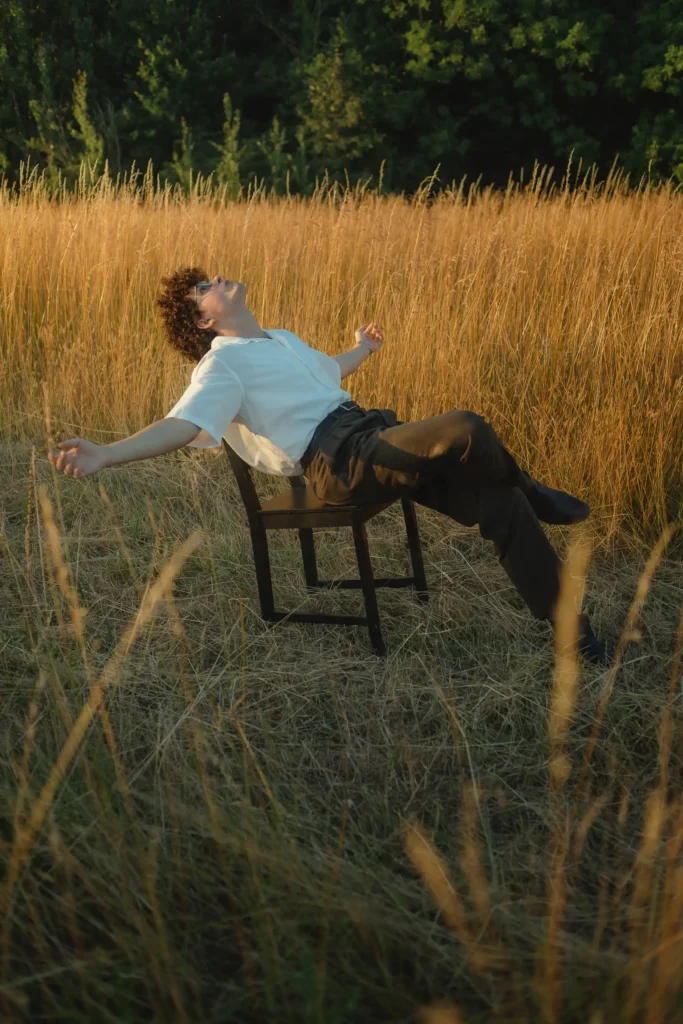 Modèle assis sur une chaise dans un champ, lumière dorée de la golden hour à proximité de Val d’Europe.