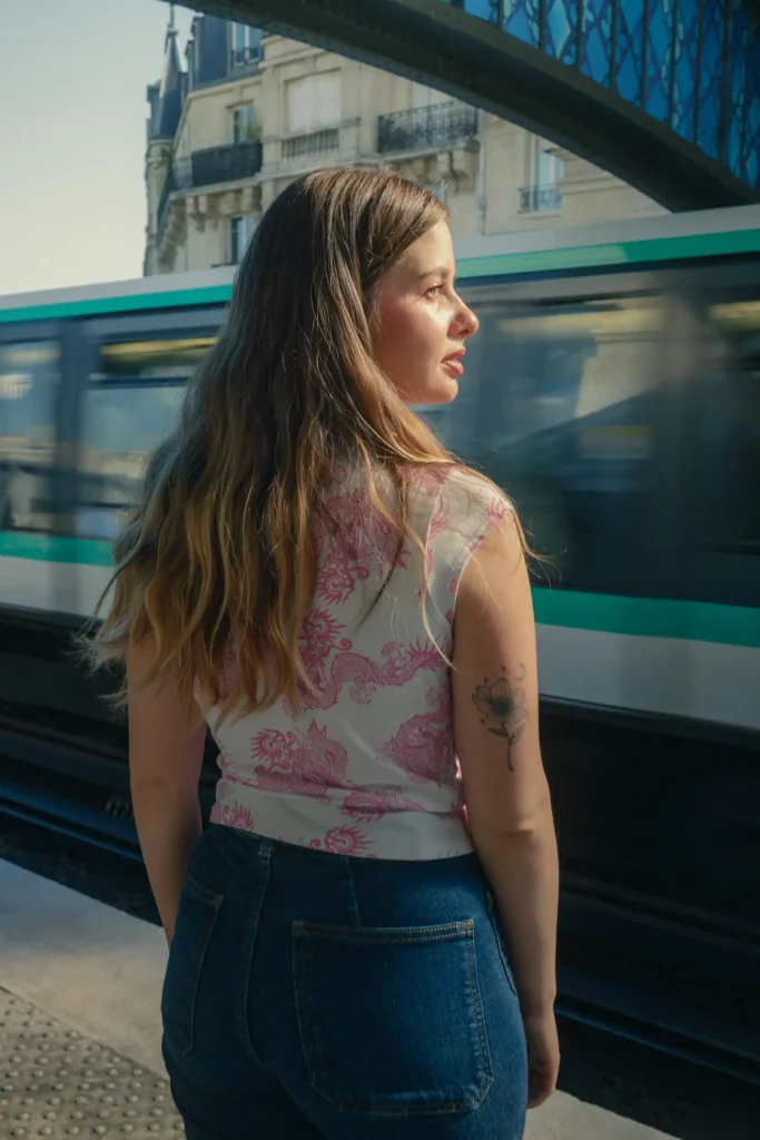 Portrait urbain à Paris d’une femme devant un métro en mouvement.