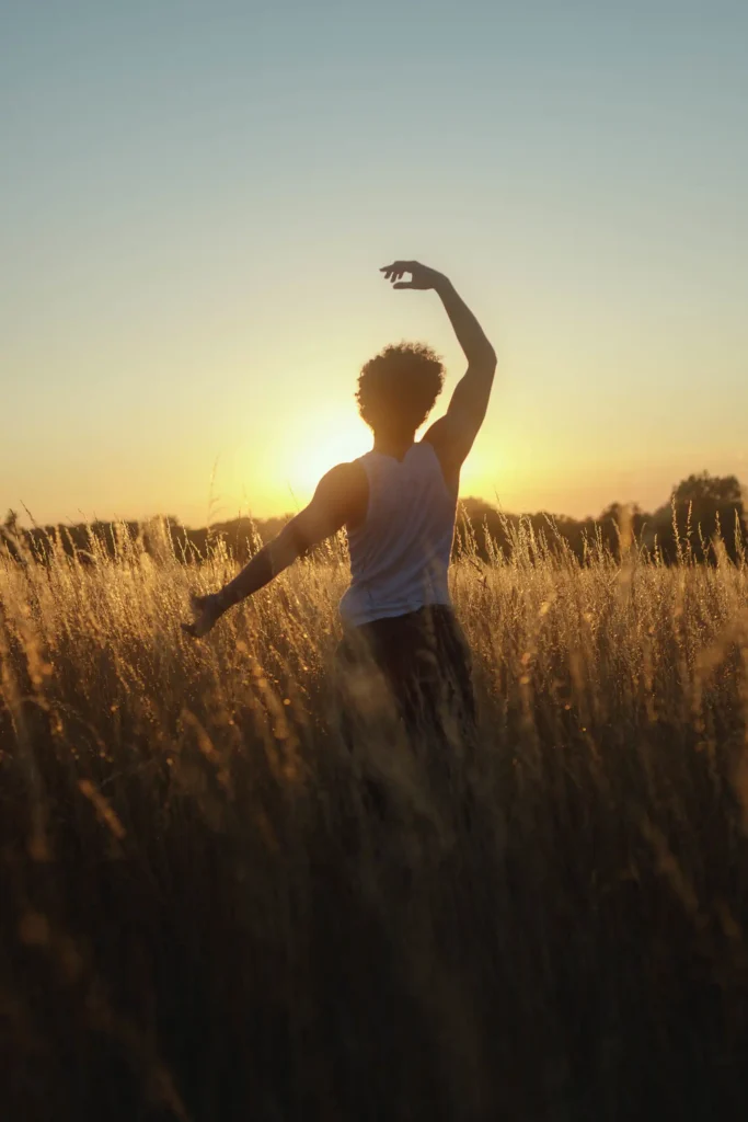 Silhouette d’un modèle dansant dans un champ à Bussy-Saint-Georges, soleil couchant en arrière-plan.